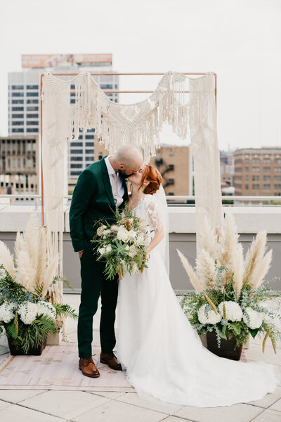 Bride & groom kissing at the alter on a rooftop in a city