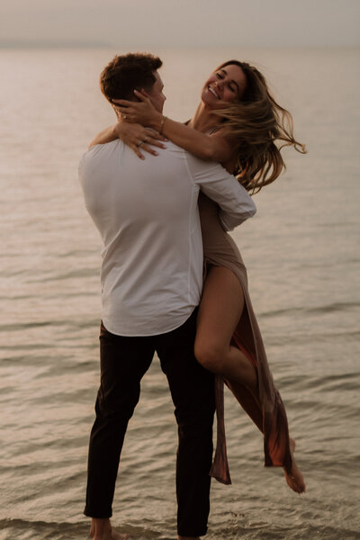 engagement session man spinning woman around in the water