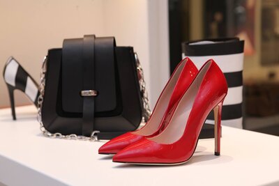 Pair of red high heels sitting next to a black purse