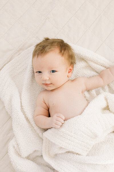 casual newborn baby photography on white bedspread window light