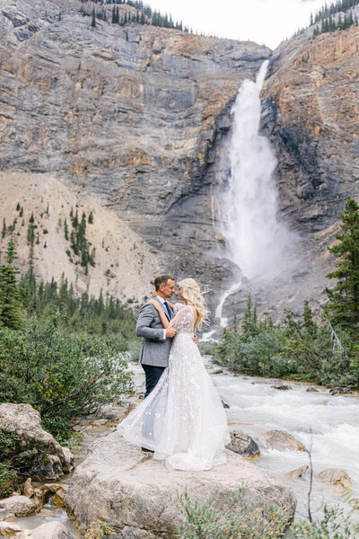 This breathtaking photograph captures the bride and groom holding each other in front of the majestic Takakkaw Falls in Yoho National Park. The powerful waterfall serves as a stunning backdrop for their intimate elopement, highlighting the natural beauty and love they share.