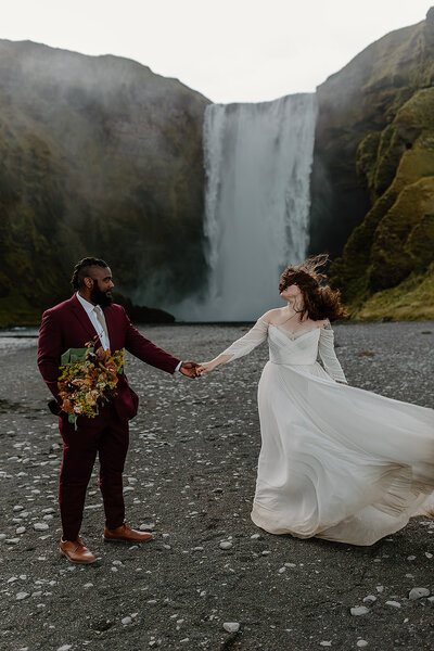 Bride and groom standing in front of Skogafoss during their iceland elopement