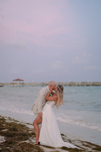 bride and groom holding hands while walking on the beach