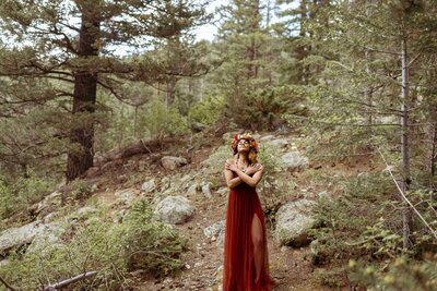 woman with a flower crown and a red dress standing in the forest