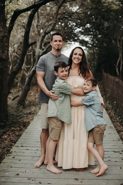family of four standing on boardwalk while smiling at the camera