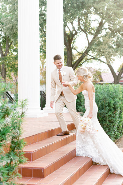 Bride and groom walk up front steps of woodbine mansion in texas