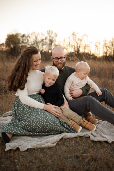 Family with two small children sitting on a blanket together on a fall day