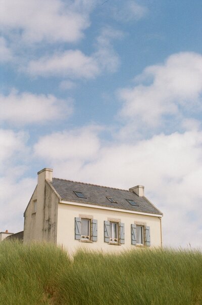 House by the sea in Finisterre France with blue skies and fluffy clouds