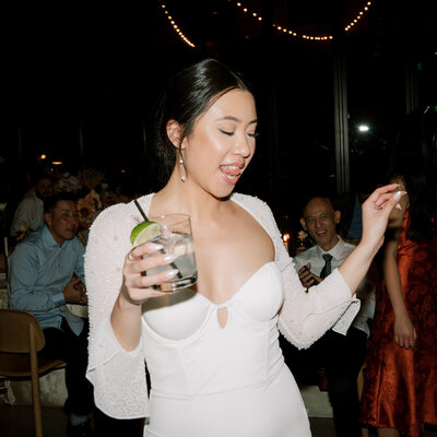 Bride holding drink and dancing at reception planned by Bianca Nichole and Co