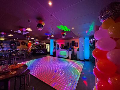Kleurrijke dansvloer in een feestzaal met discoverlichting.