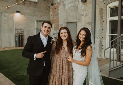 Cassandra standing with her bride and groom smiling at the camera