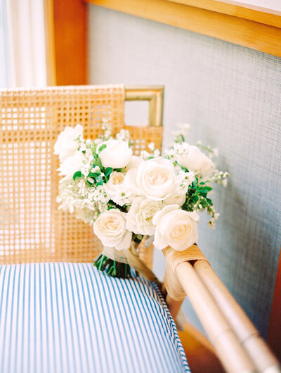white rose wedding bouquet gently placed on a nautical striped chair