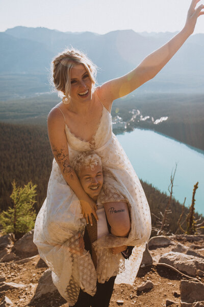 bride and groom eloping at Lake Louise in Banff National Park. Bride sitting on groom's shoulders having a good time