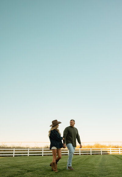 A man and woman are smiling at each other. Her arm is around his neck and his hand is around her waist.