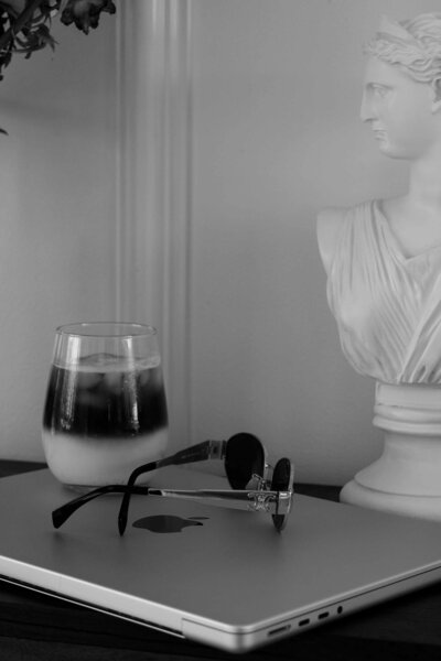Iced coffee, sunglasses, and sculpture beside closed laptop – Bespoke Web Design