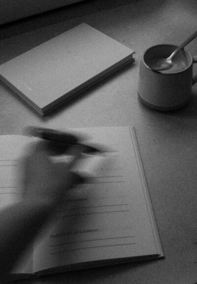 Journalling with a pen in a neutral-toned notebook, symbolising manifestation and mindset coaching practices.