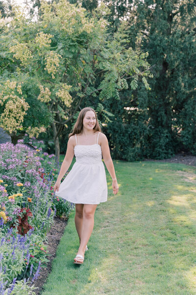 Senior girl walking through flowers during portrait session at Hershey Gardens