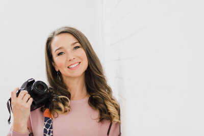 Amber Leach of Plymouth Marketing Agency Established By Her leaning against a wall whilst holding a camera