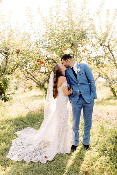 Bride & Groom kissing in an apple orchard at The Weston Red Barn Farm