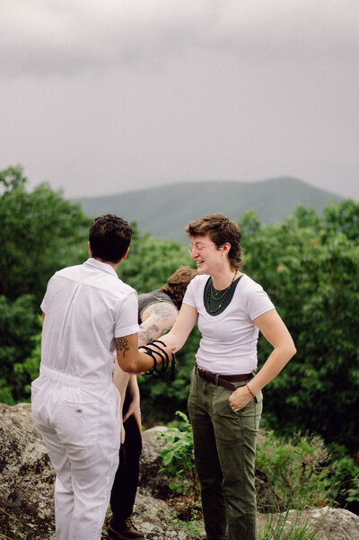 Cinematic wide shot of the couple embracing on the summit, with soft focus and natural light.
