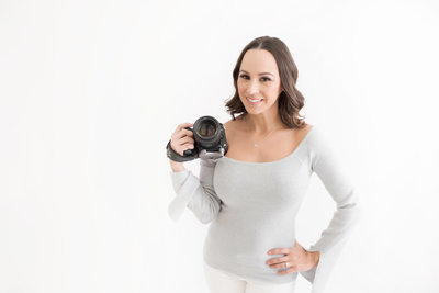 a woman holding a camera with her other hand on her hip