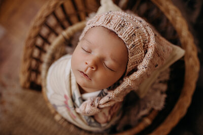 Newborn girl wrapped in a floral blanket in a backet at the Racine Business Center Studio.