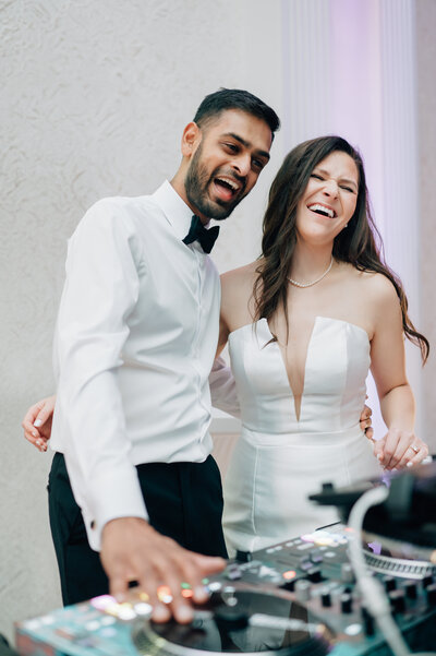 Bride and Groom play DJ at their wedding reception. Photo by Anna Brace, a wedding photographer in NE.