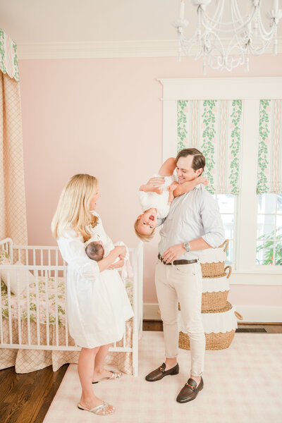 Parents holding toddler and newborn in pink nursery -Newborn Photography Greenville SC