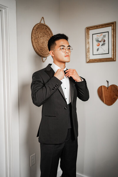 A groom adjusting his bow tie