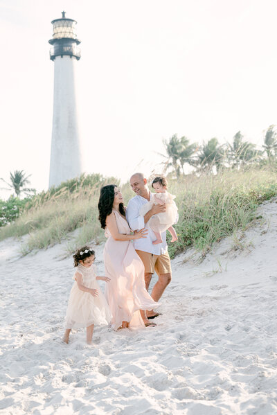 mom and dad with their daughters playing on the beach in key biscayne