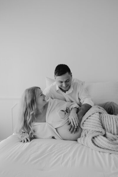 Pregnant couple snuggling on the bed.