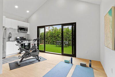 Bright and airy accessory dwelling unit featuring an indoor gym space with yoga mats, a stationary bike, full kitchen, and sliding doors opening to a private backyard