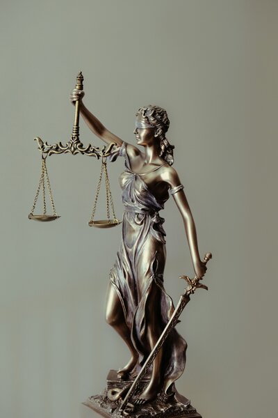 Detailed bronze statue of Lady Justice with blindfold, sword, and scales, symbolizing fairness and legal integrity