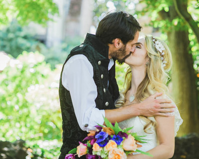 Groom has hand on Brides shoulder as they kiss