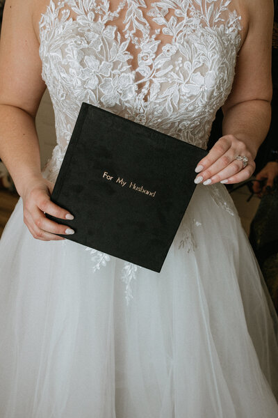 Bride holding little black book gift by Boudoir by Kiella