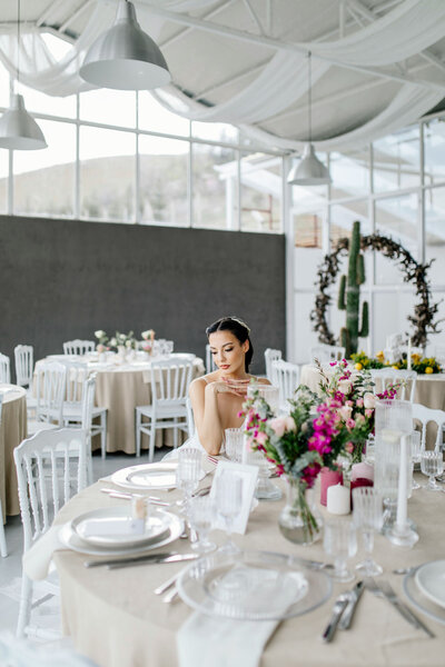 Bride sitting at a decorated reception table with floral centerpieces