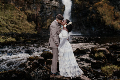 Elopement en Écosse sur l’Isle of Skye, près du Old Man of Storr, avec une séance couple au pied d’une cascade – une scène sauvage et poétique immortalisée par un duo photographe vidéaste