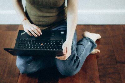 Andrea Shah sitting on the floor working on a laptop