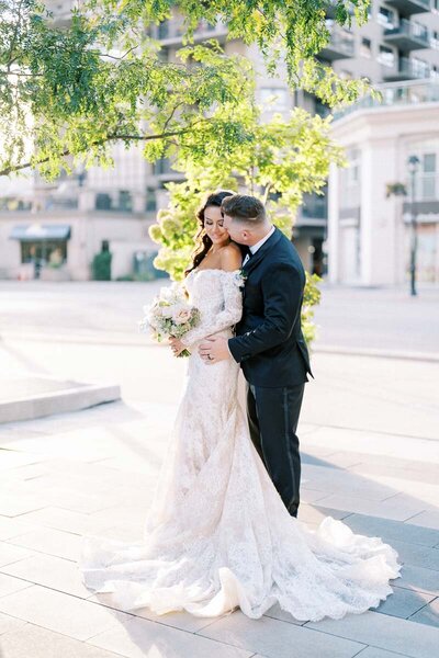 Groom kissing bride on the temple under tree light at sunset, wedding near Toronto