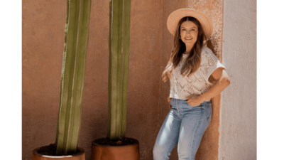 Natalie Bernacchi standing confidently against a sunlit terracotta wall beside a cactus—warm, grounded, and empowered