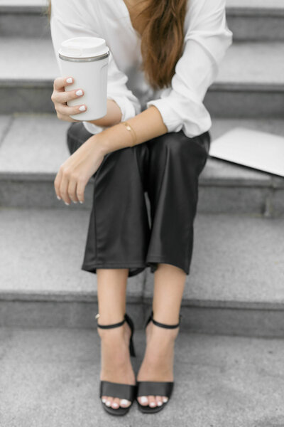Woman sitting on steps outside holding a cup of coffee