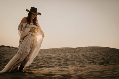 maternity photo of a woman walking in the Saskatchewan sand hills 