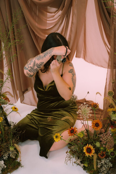 Colleen takes a photo of flowers while sitting on the ground