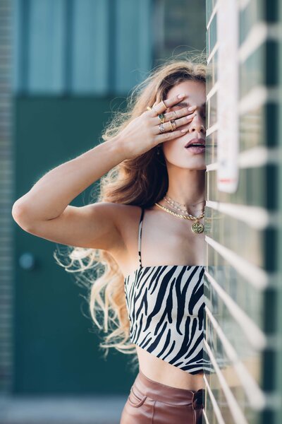 A woman in a zebra print top leaning against a wall captured by Shreveport personal branding photographer Britt Elizabeth.