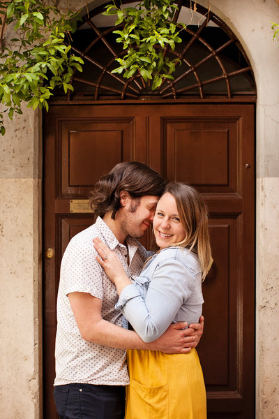 A couple in front of a brown door  embracing. Taken by Rome Couple Photographer, Tricia Anne Photography