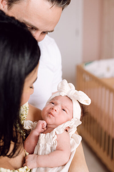 A tender in-home newborn session captured by a Northern Virginia family photographer, featuring parents holding their baby in soft natural light.