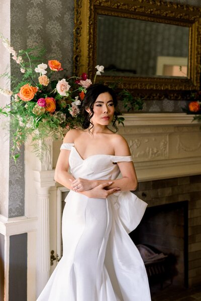 Bride posing in front of fireplace with florals
