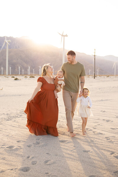 Family walking in front of windmills in southern California at golden hour. 