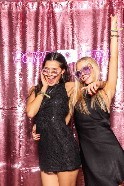 2 girls posing against a sequins backdrop and a custom neon sign, for the birthday photo booth party entertainment at no.131 in Cheltenham