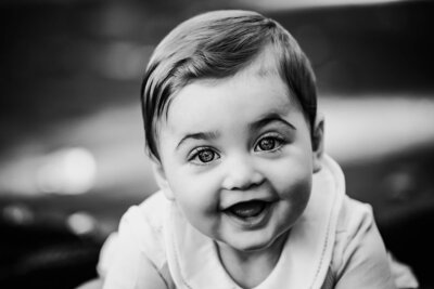 A black and white photo capturing a smiling baby during a milestone photo session.
